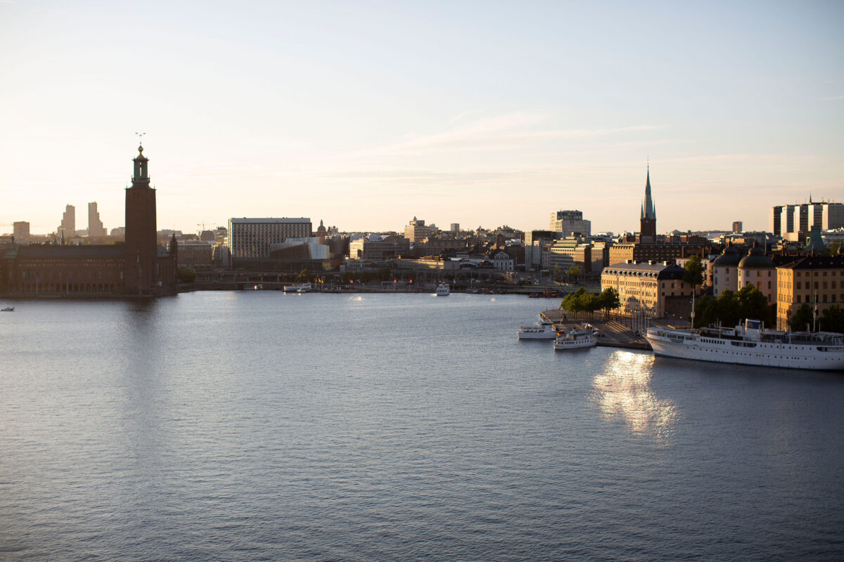 Sunset city skyline with boats, buildings, and a distant church spire